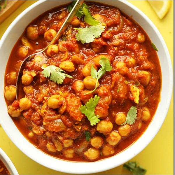 A close-up of Kaveri South Indian Restaurant's chana masala, a chickpea curry, garnished with cilantro.