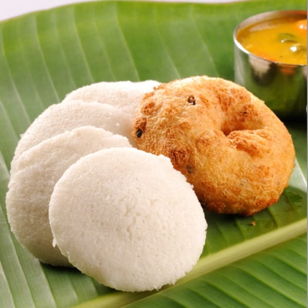 South Indian idli and vada with sambar, served on a banana leaf.