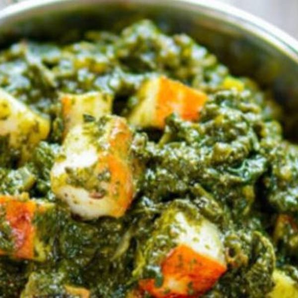 Close-up of vibrant green Palak Paneer with visible cubes of paneer cheese and spinach.